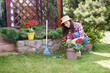 © nenadaksic - GOrgeous Caucasian brunette dressed in work wear and with hat and gloves planting pelargonium in her backyard.