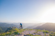 © qunica.com - Mountain biker holding his bike on a rough cliff terrain on a sunset.