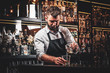 © Fxquadro - Diligent serious barman is preparing alcoholic beverege for customer.