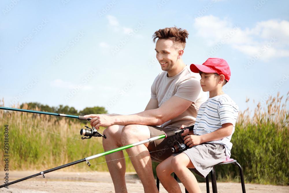 Father and son fishing together on river