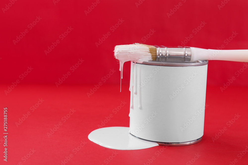 Can of paint and brush on color background