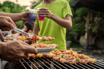 BBQ party group of people at barbecue dinner friends having food together outdoor as summer with friendship asian person.