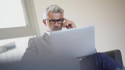 Wall Mural - Smart businessman working on laptop in airport lounge