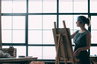 © golubovy - Fine art master class. Young lady painting, using easel. Window background. Copy space.