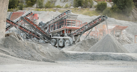 Cement production factory on mining quarry. Conveyor belt of heavy machinery loads stones and gravel. Industrial background with working gravel crusher