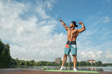 Athletic man posing with hands up, showing his muscles.