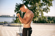 © master1305 - A muscular male athlete doing workout at the park. Gymnastics, training, fitness workout flexibility. Summer city in sunny day on background field. Active and healthy lifestyle, youth, bodybuilding.