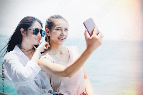 Cuadros en Lienzo Two Asian girls are using smart phones to take self-portraits while traveling