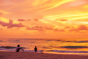 Wall Mural - Father and son relaxing on the sunset beach.