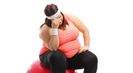 Wall Mural - Emotional overweight woman sitting on an exercise ball