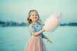 Portrait of a little girl who is resting in nature and eating cotton candy depicting pleasure and joy on the beach