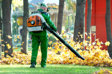 Working In The Park Removes Autumn Leaves With A Blower