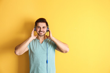 Poster - Handsome man with headphones enjoying music on color background. Space for text