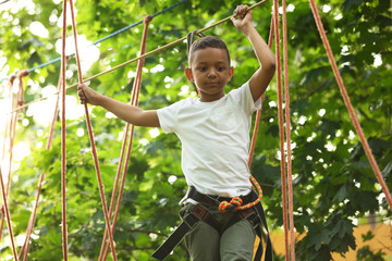 Wall Mural - Little African-American boy climbing in adventure park. Summer camp