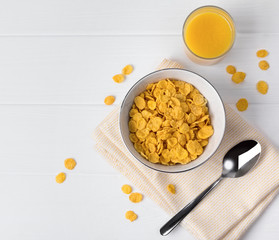 Corn flakes and glass of juice at the white table.