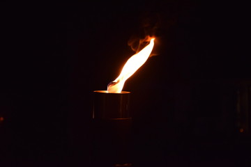 Closeup of bright flame, outdoor candle, orange and white colors, black backdrop