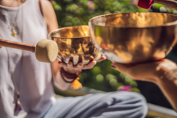 Nepal Buddha copper singing bowl at spa salon. Young beautiful woman doing massage therapy singing bowls in the Spa against a waterfall. Sound therapy, recreation, meditation, healthy lifestyle and