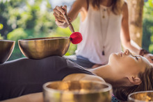 Nepal Buddha Copper Singing Bowl At Spa Salon. Young Beautiful Woman Doing Massage Therapy Singing Bowls In The Spa Against A Waterfall. Sound Therapy, Recreation, Meditation, Healthy Lifestyle And
