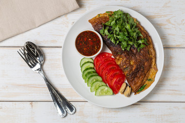 Wall Mural - Omelet with mussels. Popular Thai food served with fresh vegetables and sauce on a plate. The view from the top. Copy-space.