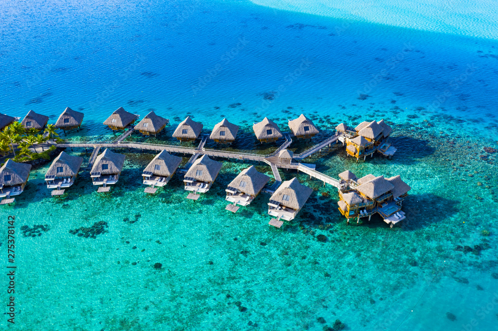 Travel vacation paradise aerial drone video with overwater bungalows in coral reef lagoon sea. Aerial video from Bora Bora, French Polynesia, Tahiti, South Pacific Ocean. - obrazy, fototapety, plakaty 