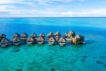 Wall Mural - Travel vacation paradise aerial drone video with overwater bungalows in coral reef lagoon sea. Aerial video from Bora Bora, French Polynesia, Tahiti, South Pacific Ocean.