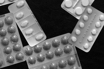 Pills and tablets blisters on a dark background close up black and white