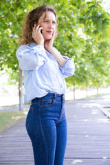 Worried concerned beautiful girl excited with phone call in park. Stressed young woman in casual speaking on cellphone, touching face and looking away Concerning phone talk concept