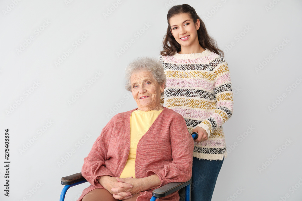 Happy woman with grandmother on grey background