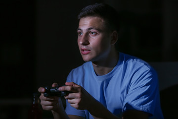 Wall Mural - Young man playing video game late in evening