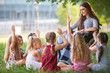 © Andrey - children hold a lesson with the teacher in the park on a green lawn.