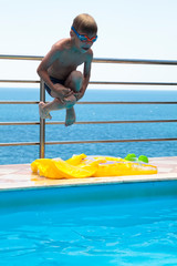 boy in a Villa on the sea jumps into the blue water of the pool with spectacular views