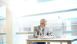 © goodluz - Mature businessman looking at cellphone in modern office