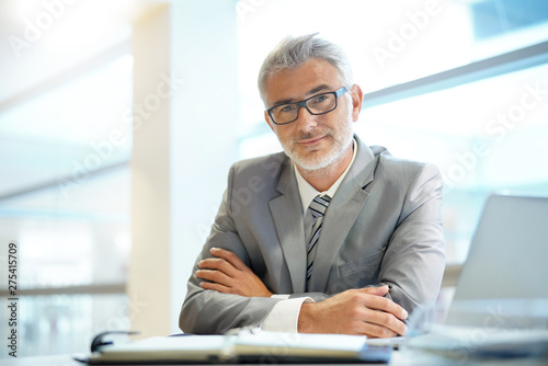 Fotomural Portrait of mature businessman sitting in office looking at camera