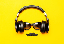 Creative Party Decoration Concept. Black Mustache, Sunglasses, Headphones For Music, Props For Photo Booths Carnival Parties On Yellow Background Top View Flat Lay. Father's Day, Men's Accessories