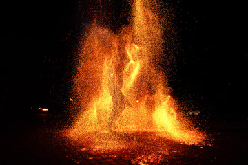 Fire show, dancing with flame, male master juggling with fireworks, performance outdoors, draws a fiery figure in the dark, bright sparks in the night. A man in a suit LED dances with fire.