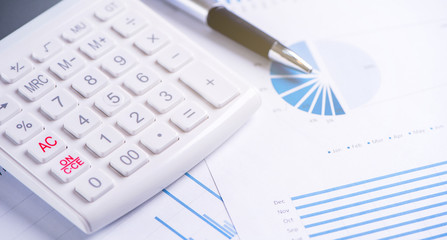 White calculator and report with chart and graph, concept of annual financial profit overview, banking and investment, copy space, macro, close up