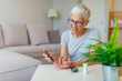 © Dragana Gordic - Mature Woman testing for high blood sugar. Woman holding device for measuring blood sugar. Woman doing blood sugar test. Woman checking blood sugar level by glucometer and test stripe at home