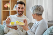 © Syda Productions - family, generation and people concept - happy smiling senior mother and adult son eating cake at home