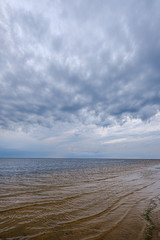 dramatic colorful clouds over sandy beach at the sea with blue sky