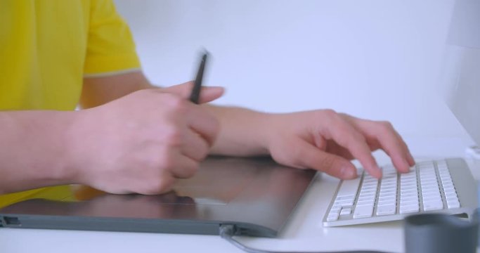 Closeup shoot of designer hands typing on the graphic touchpad indoors in the office