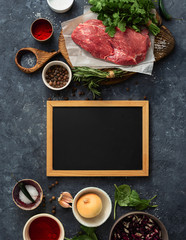 Canvas Print - Cooking table with blank chalk board and beef meat, vegetables, spices, herbs top view. Food menu