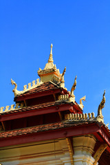 Wall Mural - Golden naga on Art Roof of Buddhist temple with blue sky in Wat Pha That Luang Temple Vientiane Province, LAOS