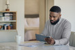 © mavoimages - African American man doing his online banking with a tablet