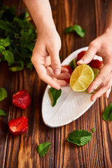 cooking of cooling summer cocktail with strawberries, ice and mint and around the berries are ripe fresh strawberries and lime