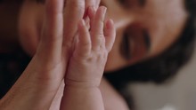 Close Up Happy Mother Holding Baby Hand Touching Fingers Nurturing Newborn Caring For Infant Enjoying Motherhood Connection With Child