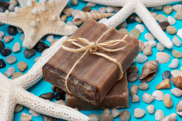 Handmade moisturizing Frankincense & Myrrh Goat's Milk Bar Soap decorated with small Pebbles, Sea Stars and Sea Shells on bright blue background.