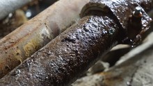 Iron Rusty Pipes Leaking In Basement Of Old House Water Drops Splashing On Pipe Repair Clamp.