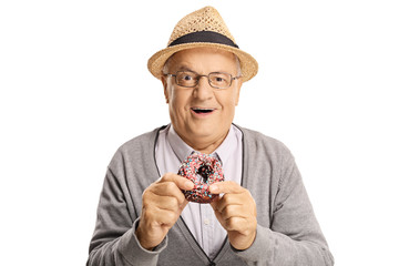 Wall Mural - Cheerful senior man eating a donut