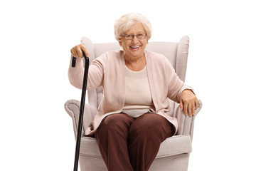 Wall Mural - Senior woman with a cane sitting in an armchair