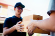 © wutzkoh - Asian cargo carrier holds a cardboard box with the package inside and the recipient is signing the package.